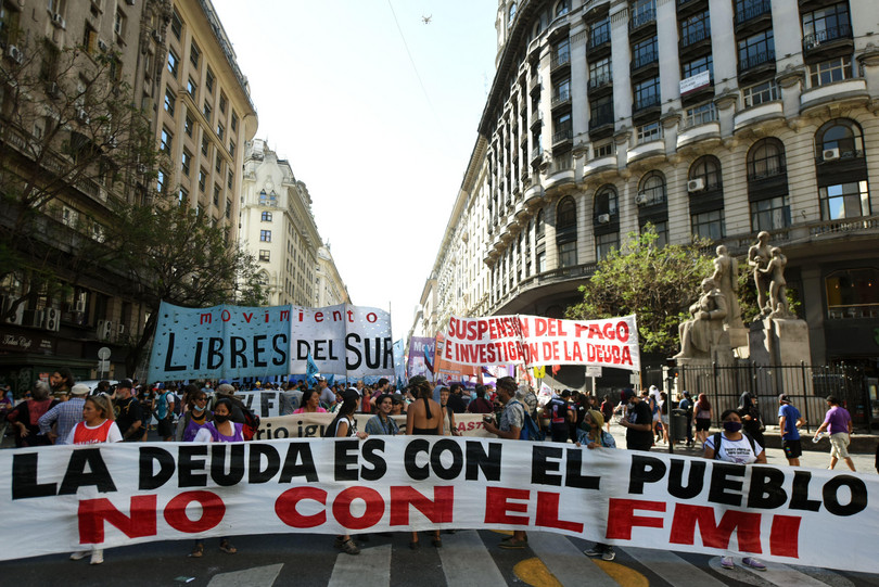 Protests against the IMF in Buenos Aires, Argentina. A crowd of people hold a large banner reading 'La dueda es con el pueblo / no con el FMI' ('The debt is with the people / not with the IMF').